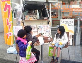 ケータリングカーの前でクレープを食べる子ども達